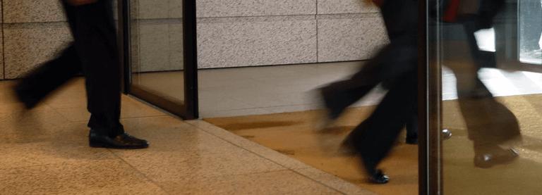 Cropped image of men in business suits walking quickly through a hallway