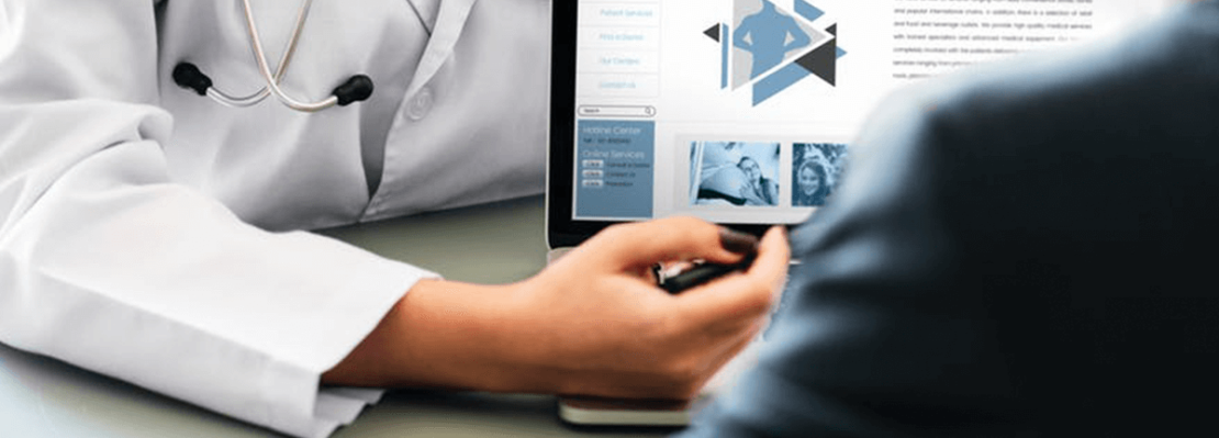 Doctor meets with a patient and points at information on a computer