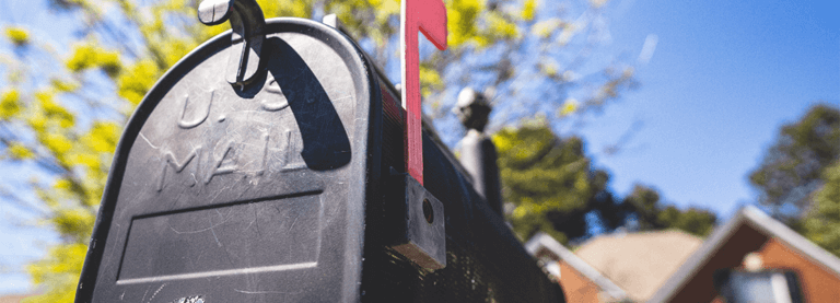 a mail box in front of a house and a blue sky