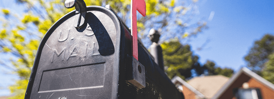 a mail box in front of a house and a blue sky