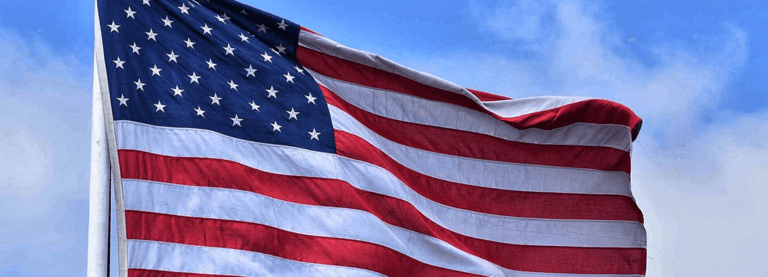 An American flag with a blue sky in the background