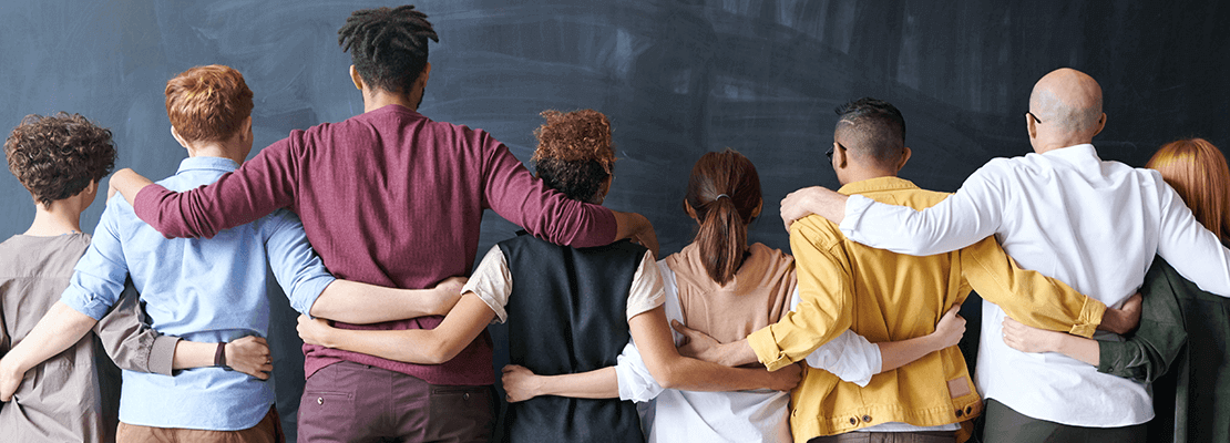 Photo: a diverse group of people, arm in arm, with their backs turned to the camera