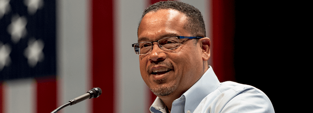 Image of Attorney General Keith Ellison standing at a podium and smiling
